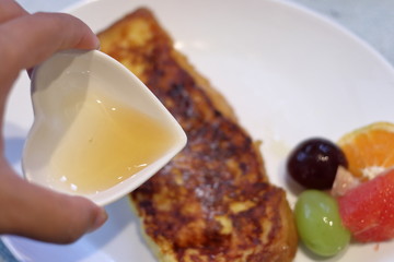 フレンチトーストに蜂蜜をかける女性