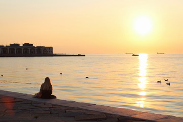 Ragazza sola al tramonto sul molo