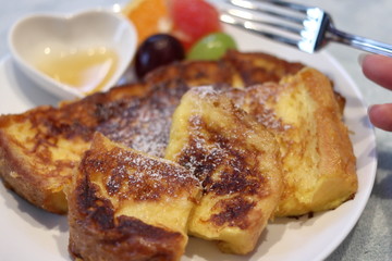 フレンチトーストをフォークで食べる女性