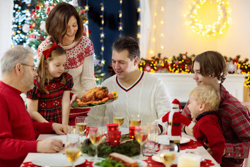 Family with kids having Christmas dinner at tree
