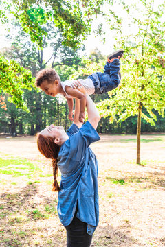 Mother Tossing Up Son For Fun In Park In Sunny Day