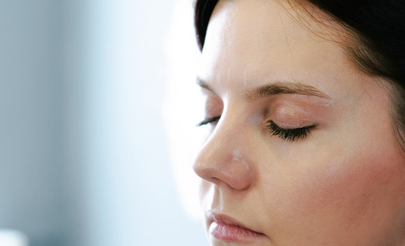 Closup fce of woman brunette looking down. Right on photo, side view.