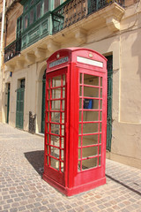 Empty telephone red booth in Marsaxlokk, Malta in sunny day