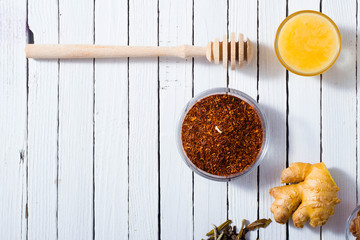 cup of tea, different leaves, honey, lemon ginger and brown sugar on white wooden table background