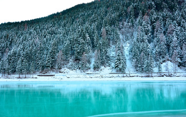 the frozen turquoise lake and the snow-covered forest