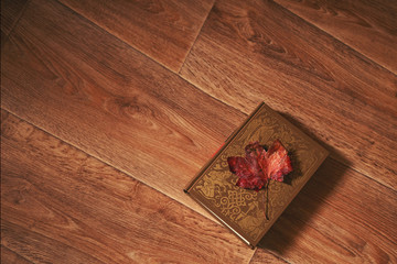 Book and red leaf of maple on wooden background