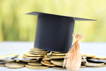 Graduation card for saving coins for scholarships for conceptual financing and education. Graduation microcline and gold coins near a book on a green background, concept of investment education, closi
