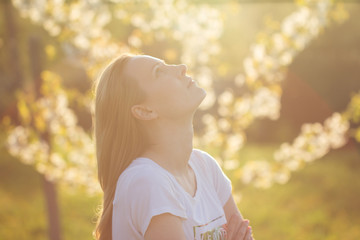 cheerful young attractive woman enjoying sunset in spring garden