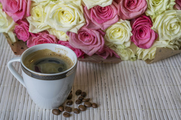 Next to a bouquet of roses is a Cup of coffee. 