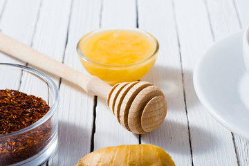 cup of tea, different leaves, honey, lemon ginger and brown sugar on white wooden table background