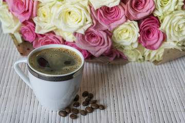 Next to a bouquet of roses is a Cup of coffee.	