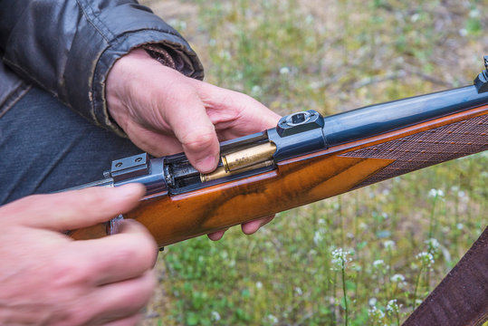 Men's hands loading the hunting carbine with bullet close up