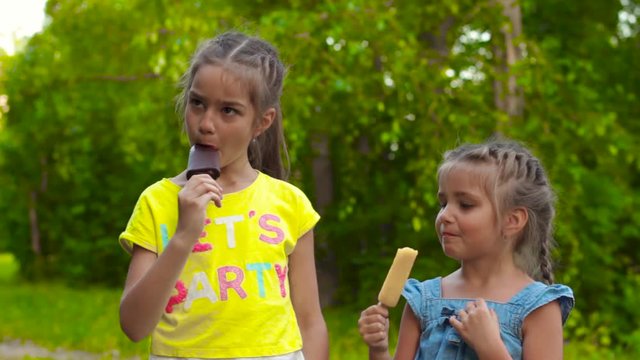 Two girls eating popsicle ice-cream in park