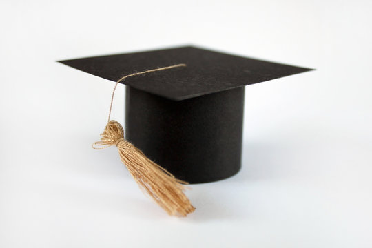 Graduation cap on saving coins for concept finance and education scholarships. Graduation mortarboard and golden coins on white background, concept investment education, close up, selective focus, cop