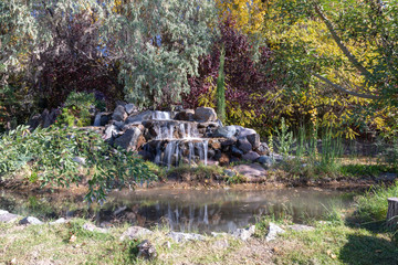 Waterfall in autumn surrounded by trees and with reflection in a pond in Mendoza Argentina