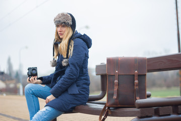 young woman with camera sitting on bench