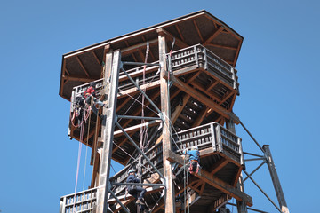 People learining safely the technic of climbing on a wooden building. saftey, worker, danger, climbing, fun, tourist, equipment;