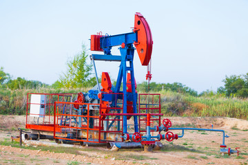 The oil pump, industrial equipment. Oil field site, oil pumps are running. Rocking machines for oil production in a private sector.