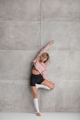 Young woman standing in Tree pose near wall