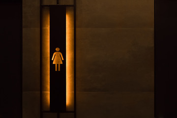 Public women's toilet room. Backlighting of dresssing room signs in public place. Female restroom sign. Restroom sign in public place. Public toilet entrance. Copy space.