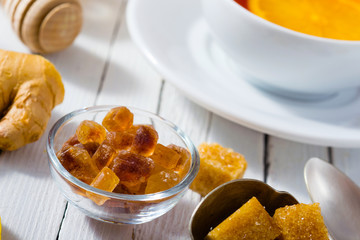 cup of tea, different leaves, honey, lemon ginger and brown sugar on white wooden table background