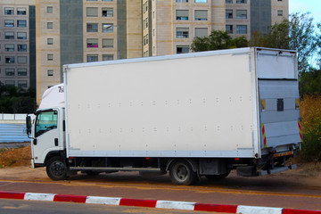 Israel: White Truck parked on the side of the road. Border in Red and White Stripes, No Parking Truck in Israel. Modern Apartment Buildings, New District of Rishon LeZion city