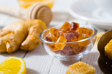 cup of tea, different leaves, honey, lemon ginger and brown sugar on white wooden table background