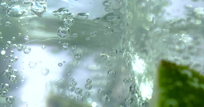 Extreme close up of ice and bubbles in a gin and tonic drink with lime