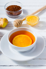 cup of tea, different leaves, honey, lemon ginger and brown sugar on white wooden table background