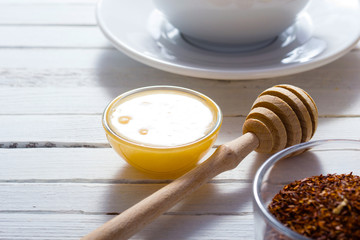 cup of tea, different leaves, honey, lemon ginger and brown sugar on white wooden table background