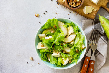 Pear Salad, Walnut, Camembert Cheese and Vinaigrette Dressing on stone table. Traditional french cuisine. Traditional french cuisine. Top view flat lay background. Copy space.