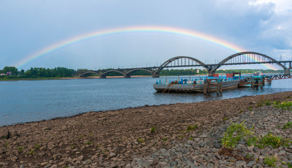 Fototapeta na wymiar Rybinsk, Yaroslavl region, Russia, August 03, 2013: View from embankment on bridge over Volga river and rainbow 