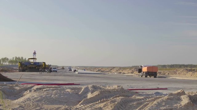 Construction, concreting of airport runways roads. Men, workers working with asphalt paver, resting. Roadroller, construction machinery works on new runway construction of national airport Minsk, MSQ