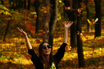 девушка бросает листья в лесу. - obrazy, fototapety, plakaty