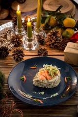 Russian traditional salad Olivier with slices of salmon on top with new year decoration on wooden table