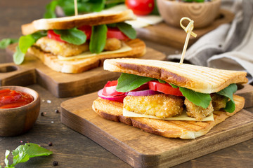 Sandwich with Tomatoes, Cheese, Crispy Chicken Nuggets and Arugula.  Delicious fresh homemade club sandwich with chicken on a wooden table. Fast food.