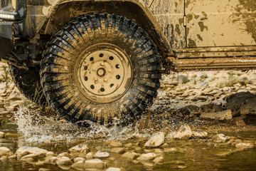 Off road sport truck between mountains landscape. Bottom view to big offroad car wheel on country road and mountains backdrop. 4x4 travel trekking.