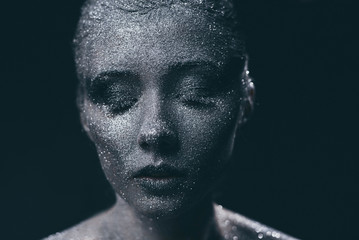 Portrait of beautiful woman with silver sparkles on her face. Fashion model with colorful make-up.