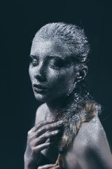 Portrait of beautiful woman with silver sparkles on her face. Fashion model with colorful make-up.