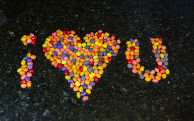 I love you, spelled with candy beans on dark background