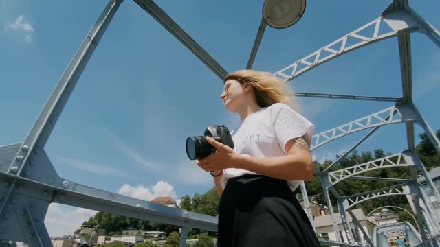 Wide angle shot on sunny summer day of young attractive blonde woman, female photographer makes photos of european town, salzburg, explores travel blogger destination for holidays