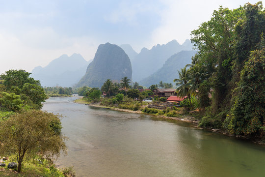 Scenic view of the Nam Song River, Pha Tang village and limestone mountains near Vang Vieng, Vientiane Province, Laos, on a sunny day.