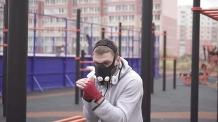 Man in a training mask on his face boxing on a sports street playground,slow mo