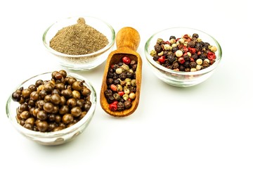 Pepper in wooden spoon. Mix of different peppers balls on white background. Sale of spices.