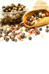 Pepper in wooden spoon. Mix of different peppers balls on white background. Sale of spices.