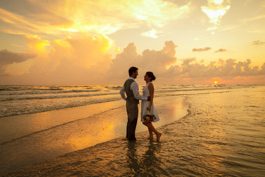 silhouette of bride and groom at sunset on beach