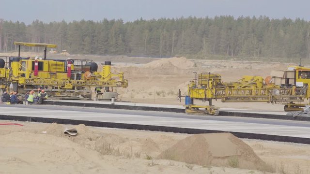 Construction, concreting of airport runways roads. Men, workers working with asphalt paver, resting. Roadroller, construction machinery works on new runway construction of national airport Minsk, MSQ