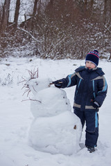 child sculpts snowman,  child for a walk