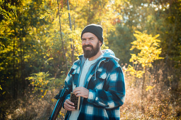 Hunter with shotgun gun on hunt. Bearded hunter man holding gun and walking in forest.