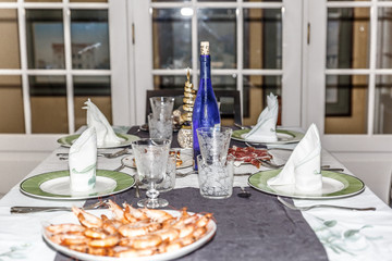 View of a Christmas table with dishes, glasses, bottle, prawns